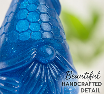 Close-up of a blue gonk figurine with honeycomb pattern, text 'Beautiful Handcrafted Detail' on a blurred green background.
