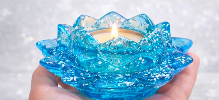 Blue Resin lotus-shaped candle holder with a lit candle on a blurred background