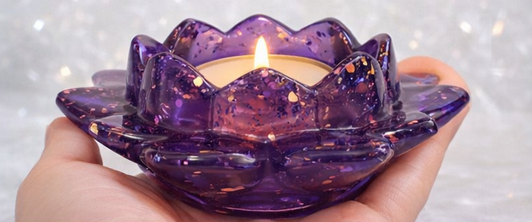 Purple Resin candle holder with a lit candle inside, held by a hand against a blurred background.