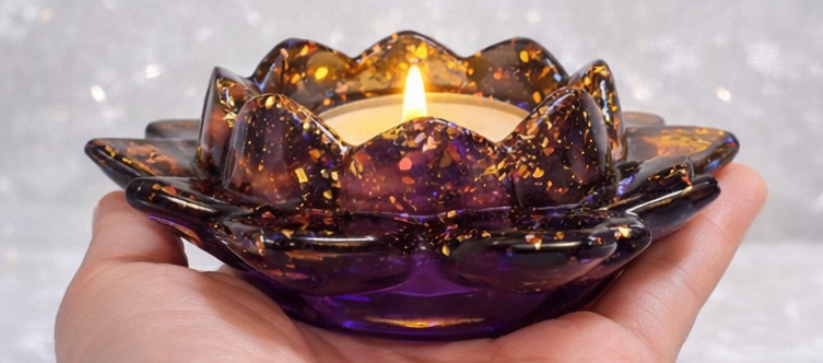Hand holding a purple Resin candle holder with a lit candle against a glittery background