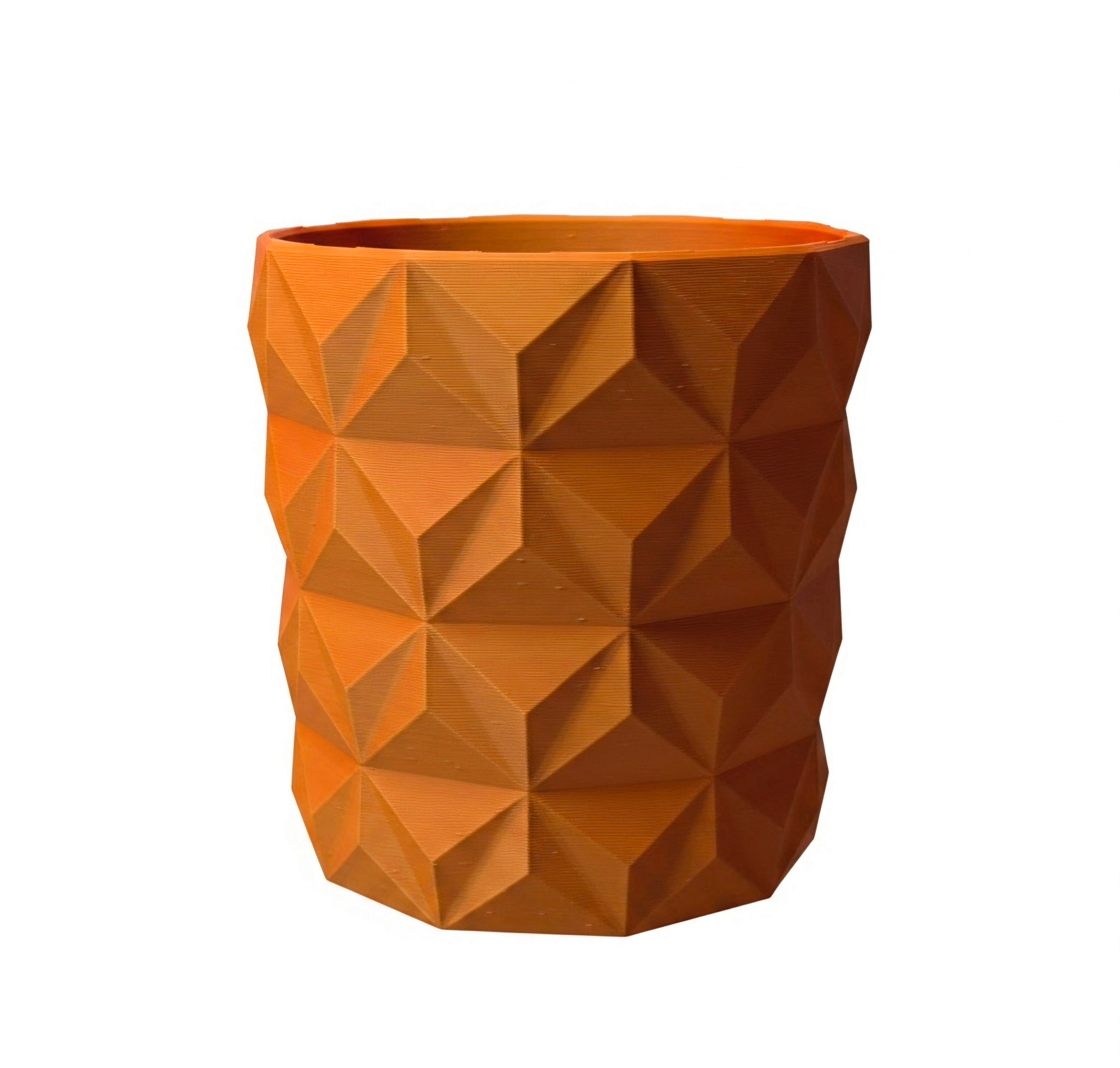 An orange planter with a geometric, faceted 3D design, shown against a plain white background.