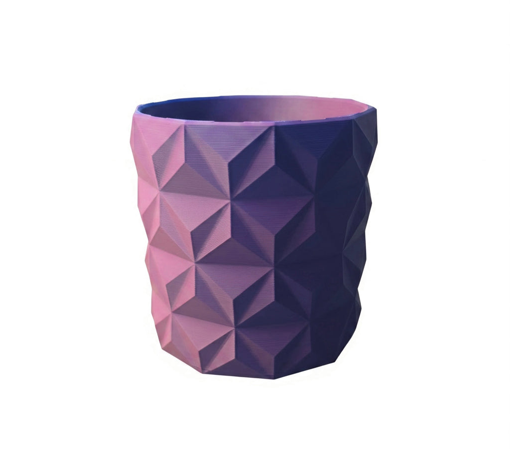 A modern geometric planter with a faceted, low-poly design, featuring a color gradient transitioning from pink on the left to deep purple on the right, set against a plain white background.